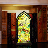 Book nook display with stained-glass style front panel and base on bookshelf