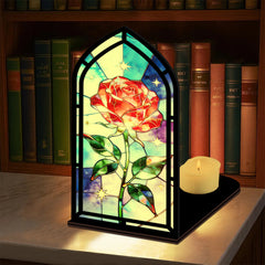 Black arched book nook with stained-glass red rose panes, with lit candle on the base