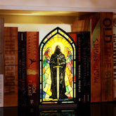 Stained-glass arched book nook display with hooded knight holding sword, on black base