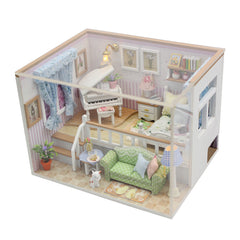Miniature dollhouse room kit seen from above with green sofa, piano, bed and lamp