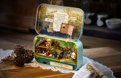 Miniature theater diorama tin with rustic farmhouse scene, open on fabric and lace