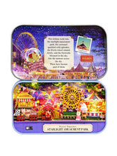 Mini amusement park diorama in a blue metal tin with colorful illuminated rides and Ferris wheel