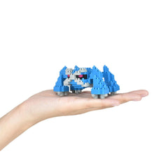 A hand holding a small blue and white toy, which appears to be a pixelated or miniature version of a character or object.