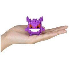 A hand holding a small, purple, pixelated character resembling a Pokémon.