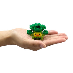 A hand holding a small green toy resembling a tree or plant.