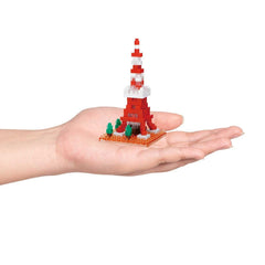 A hand holding a small red and white tower made of colorful building blocks.