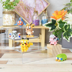 a collection of colorful pixel art figurines and a variety of potted plants arranged on a wooden surface.