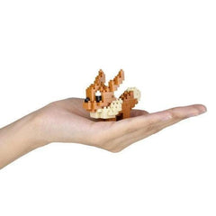 A hand holding a small, brown and white pixelated animal figure.