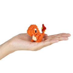 A hand holding a small orange pixelated character, resembling a Pokemon or similar character.