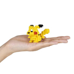 A hand holding a small yellow pixel-based character, resembling a pixel art style Pokemon.