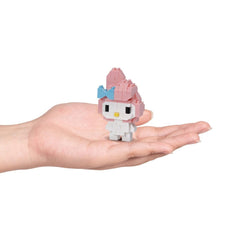 A hand holding a small, pink and white Hello Kitty-style figure.