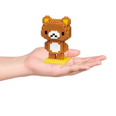 A hand holding a small brown bear-shaped building block figure.