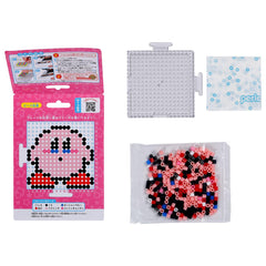 a pink box with a picture of a character, a clear plastic container filled with colorful beads, and a small white square with blue dots.