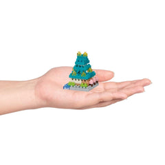 A hand holding a small, colorful, and intricate toy or model, resembling a miniature version of a larger structure or object.