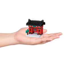 A hand holding a small, colorful, and intricate model of a building or structure.