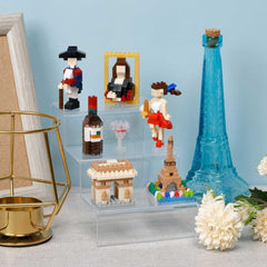 a collection of miniature figurines and objects, including a blue bottle, a golden candlestick holder, and a framed picture, all displayed on a shelf or table.