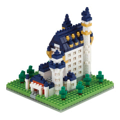 A small, colorful, and intricate model of a castle made out of building blocks, including a tower, turrets, and a grassy landscape.