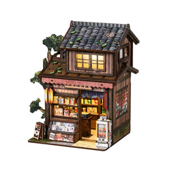 Miniature wooden Japanese grocery store model with lit windows, tiled roof, and shelves