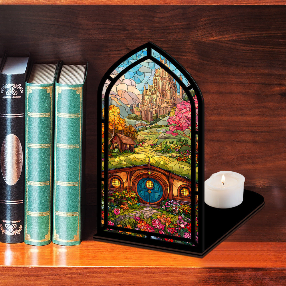 Arched book nook display with colorful illustrated panel and lit candle on a black base.