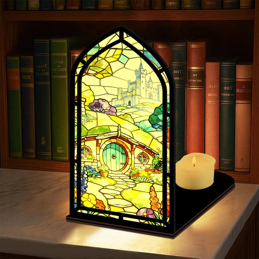 Book nook display with stained-glass style panel and small lit candle on base