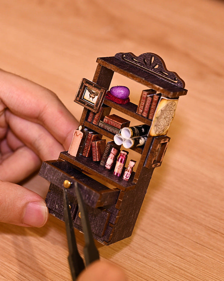 Wooden miniature book nook with tiny chairs, books, and purple lamp
