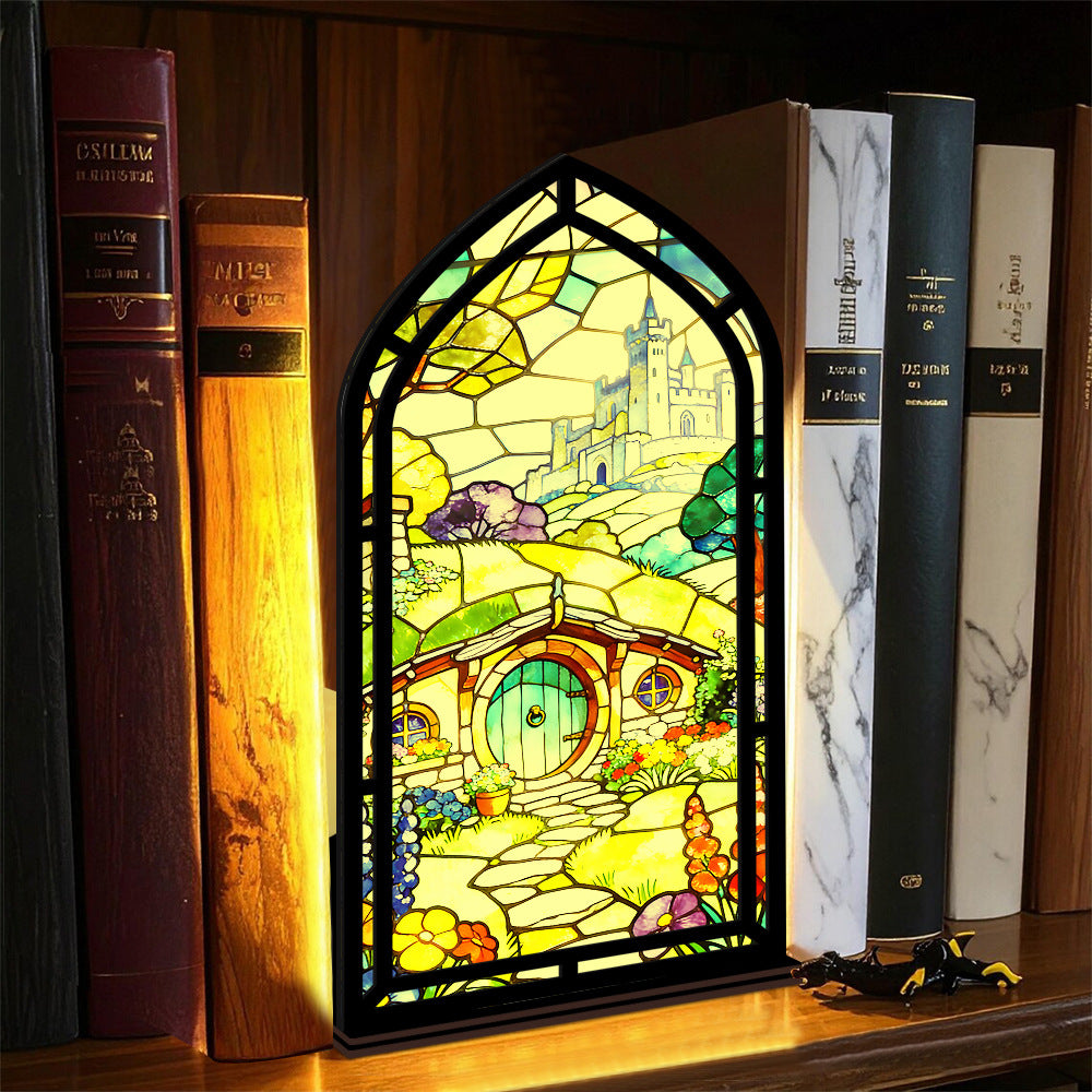Book nook display with stained-glass style panel and warm-lit candle on base