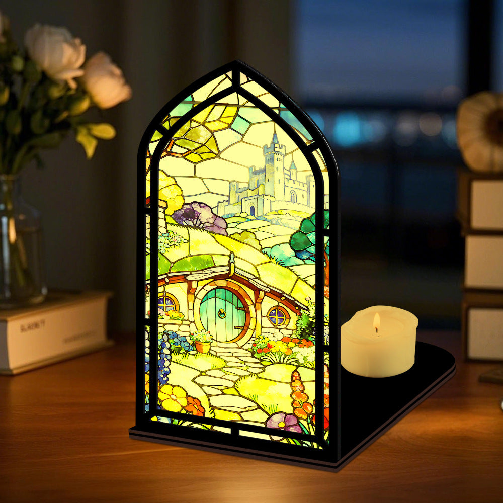 Book nook display with stained-glass style panel and lit candle on tabletop
