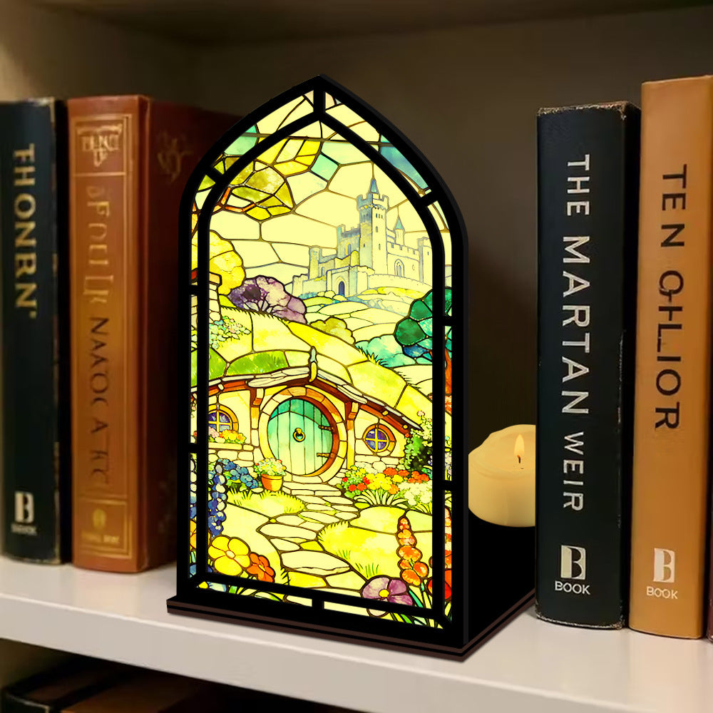 Book nook display with stained-glass style panel and two lit candles on shelf