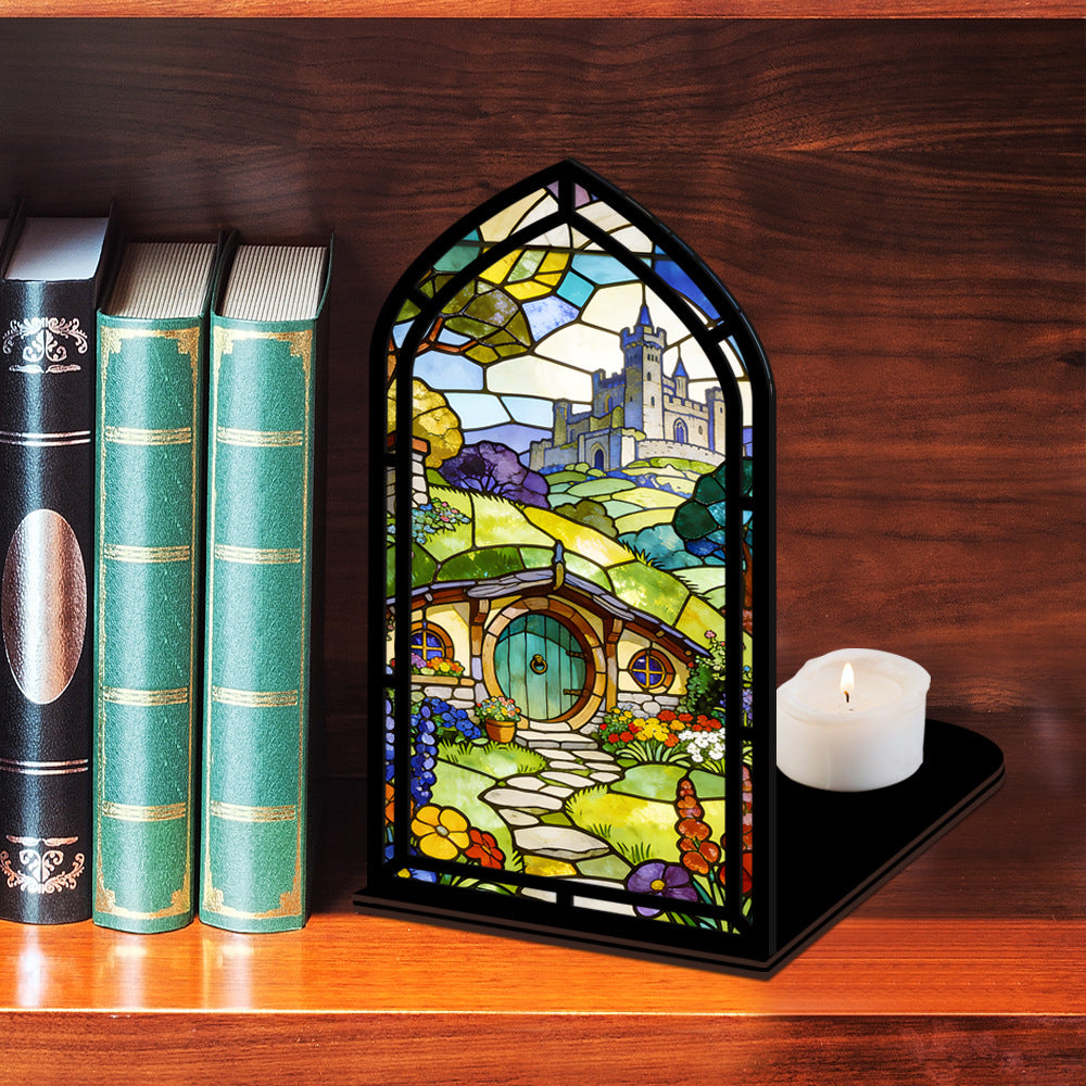 Book nook display with stained-glass style panel and white lit candle on base