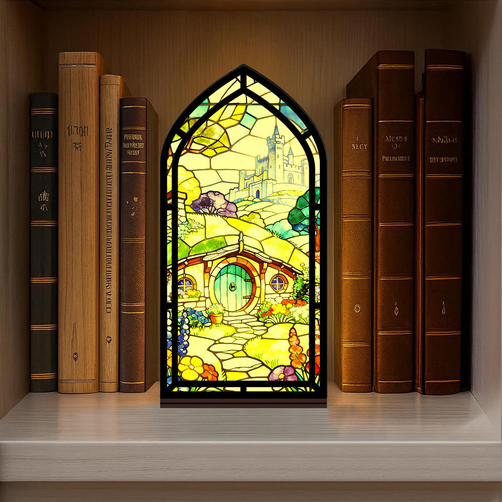 Book nook display with stained-glass style panel between books on shelf