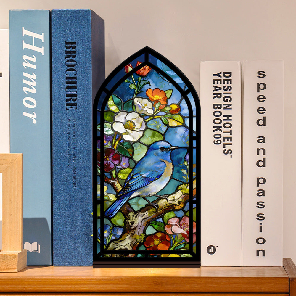 Bluebird stained-glass book nook with arched black frame, shown between books