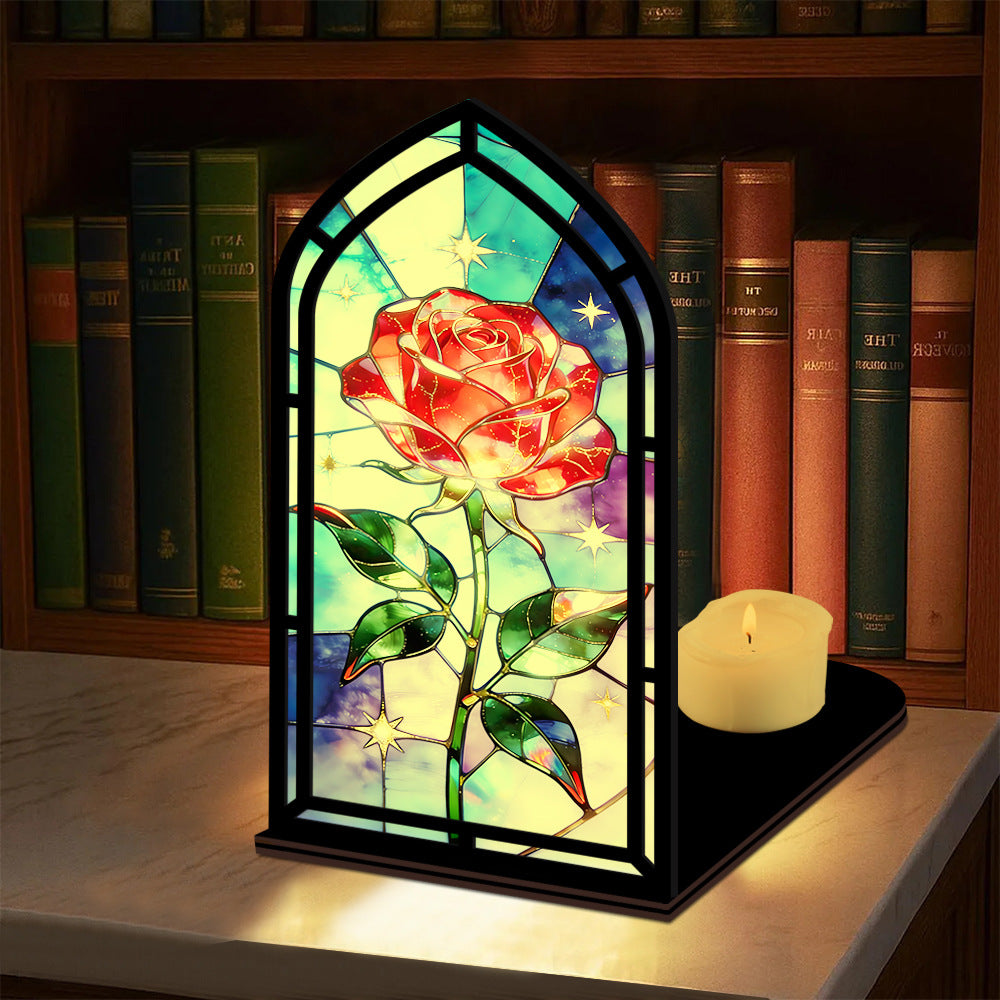 Black arched book nook with stained-glass red rose panes, with lit candle on the base