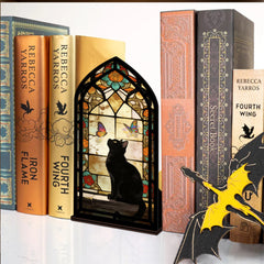 Stained glass arched book nook display with black cat silhouette, butterflies, and warm glow