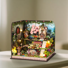 Miniature forest cabin diorama with lit lanterns and pink flowering tree
