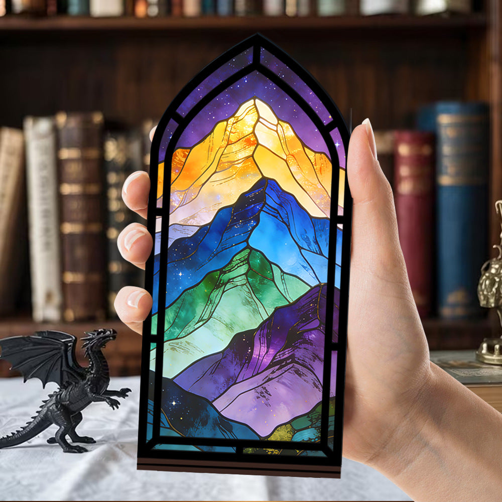 Hand holding arched lit book nook with colorful mountain scene and purple LED frame