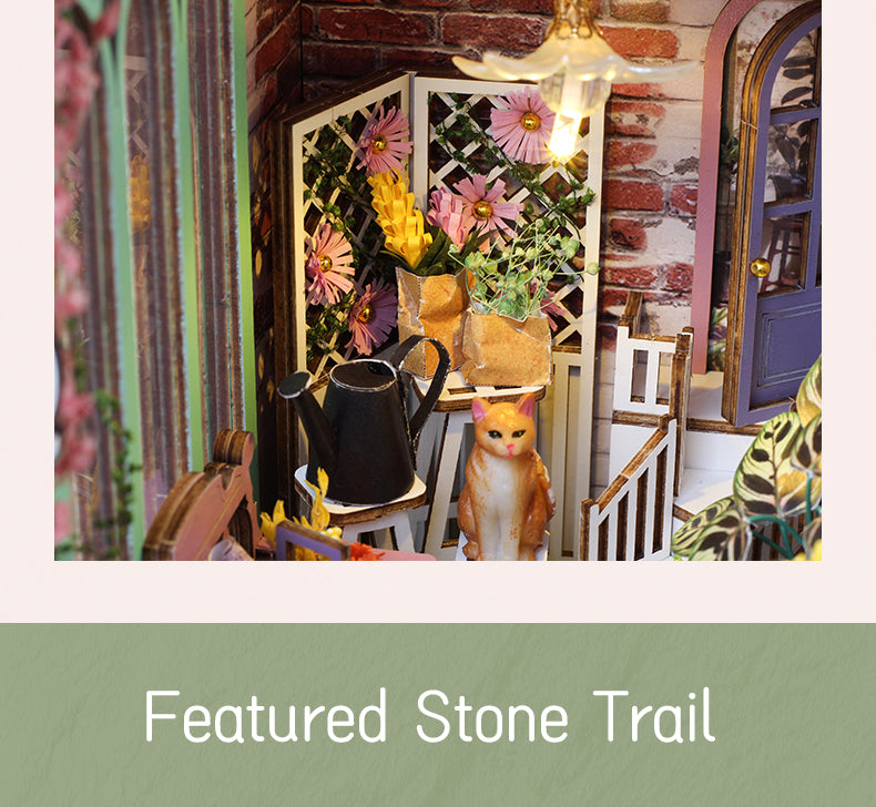 Miniature book nook exterior with flower boxes, cat figurine, and warm lantern lighting