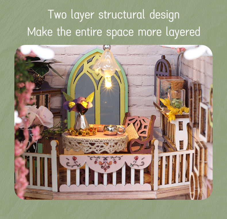 Miniature greenhouse book nook scene with lit arch lantern, floral table, and fence