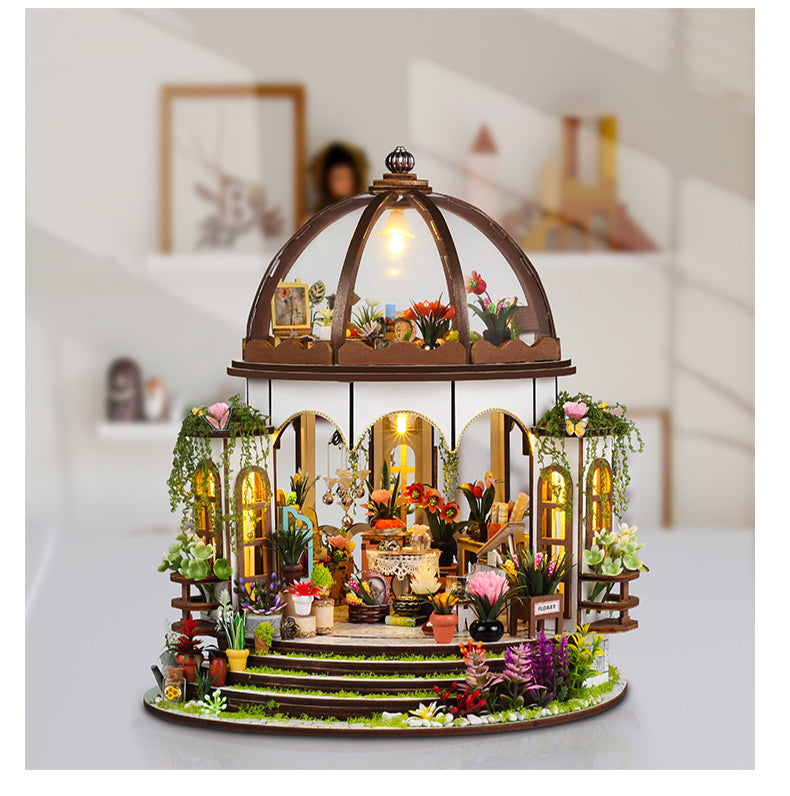 Miniature dollhouse diorama with glowing dome roof, arched windows, and miniature garden displays