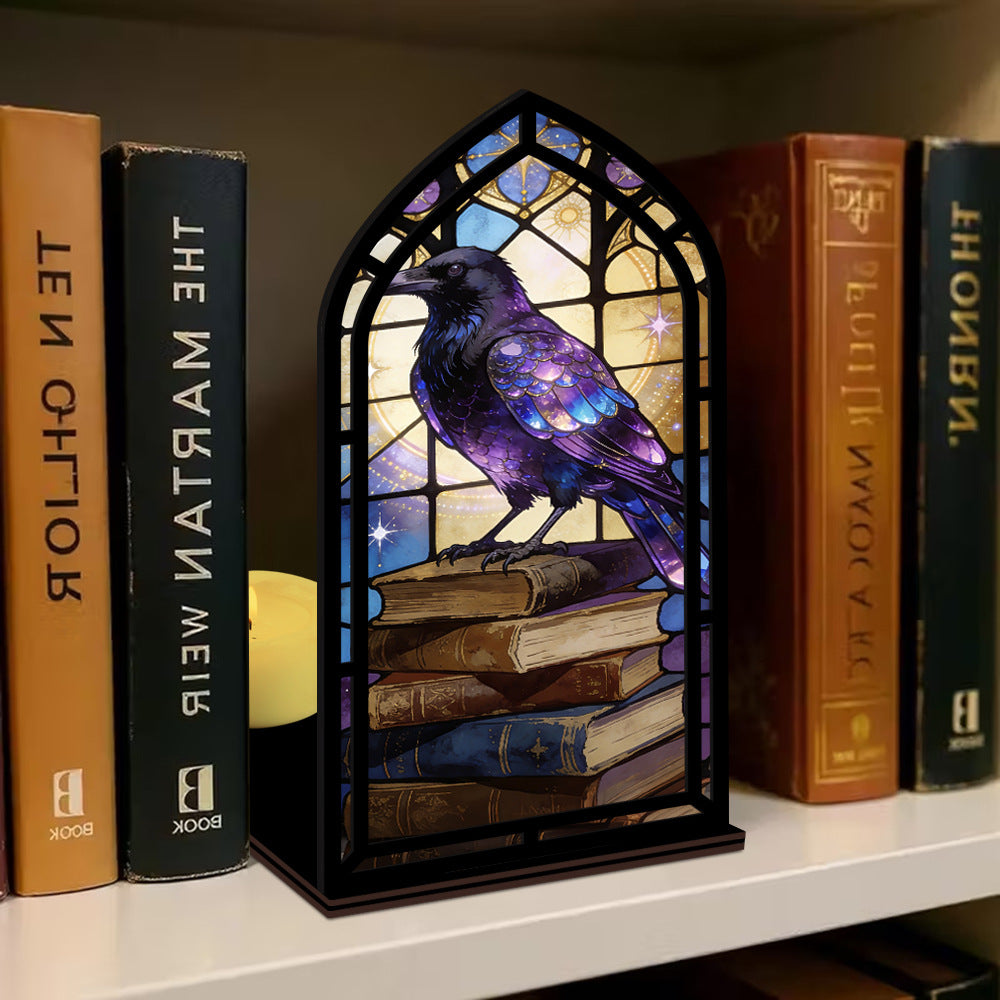 Arched book nook candle display with purple raven inside arched stained-glass frame