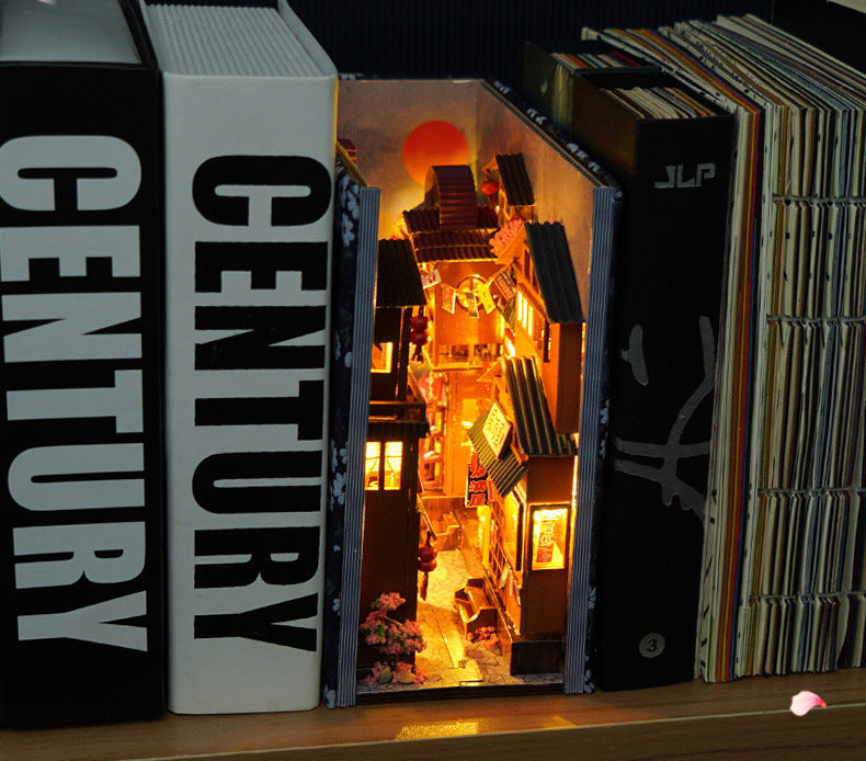 Miniature Japanese street book nook scene with warm lights and shelves in an open case