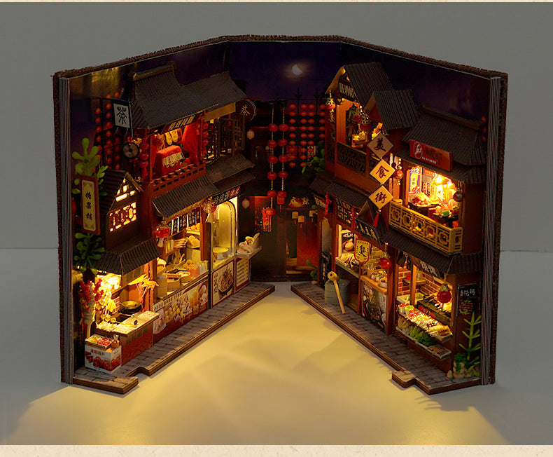 Open DIY miniature street food book nook kit showing multiple lit shopfronts and food displays.