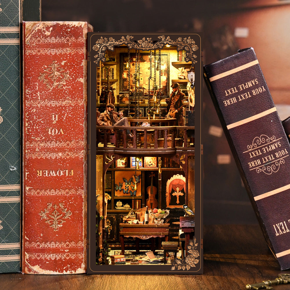 DIY book nook display case with lit interior beside stacked book volumes