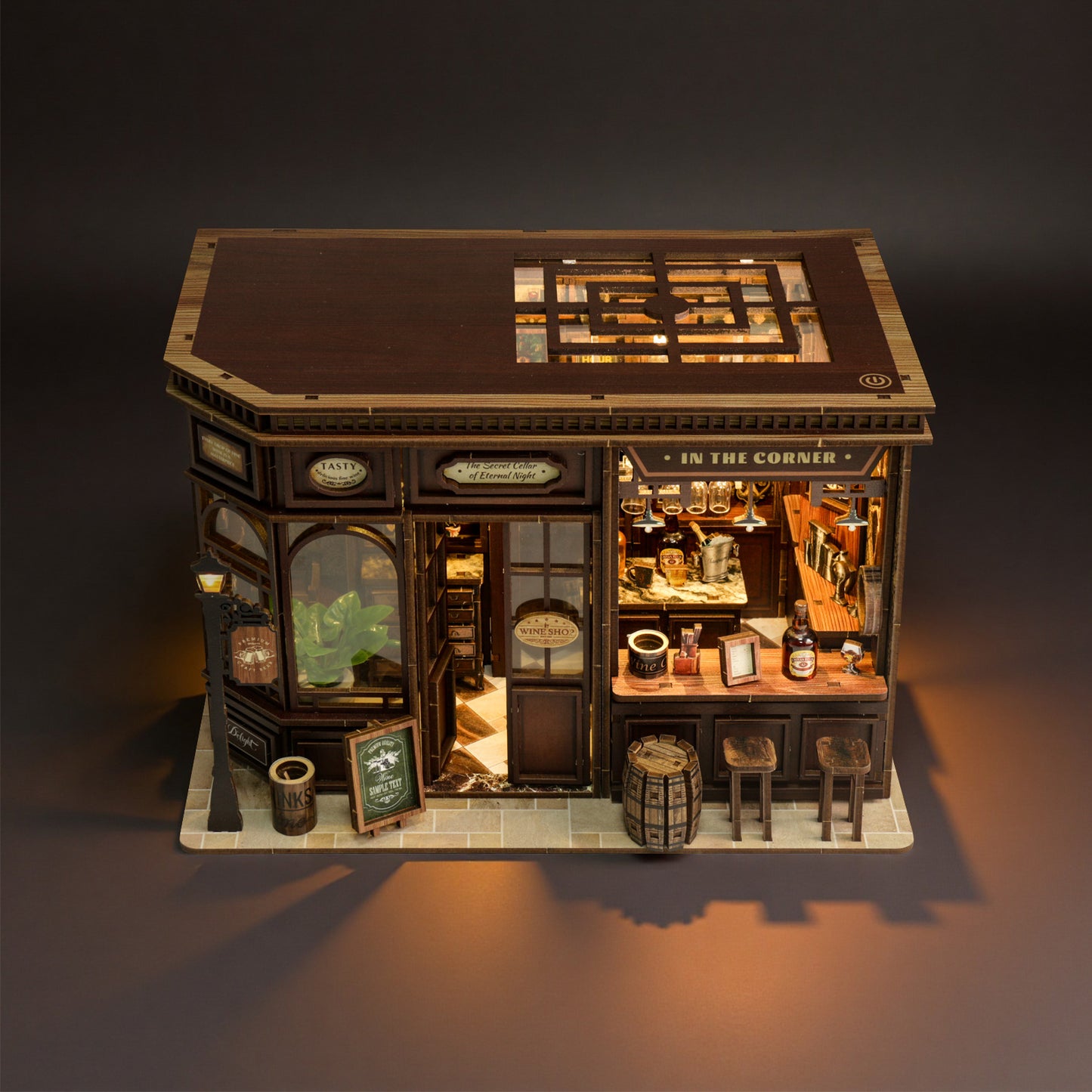 A miniature model of a quaint, old-fashioned bar or pub, complete with a small wooden bar, shelves filled with various items, and a sign that reads "In the Corner".