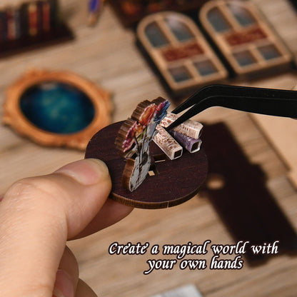 A hand is holding a small wooden object, which appears to be a miniature figurine or model, with a pair of tweezers or a small tool being used to manipulate it.