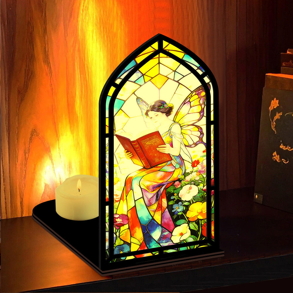 Stained glass fairy book nook with arched reading figure, black base, candle glowing beside