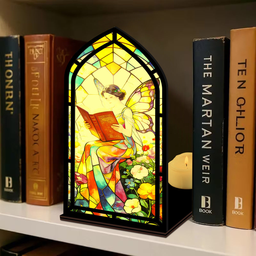 Stained glass fairy book nook display with arched reading panel, black frame, candle and books