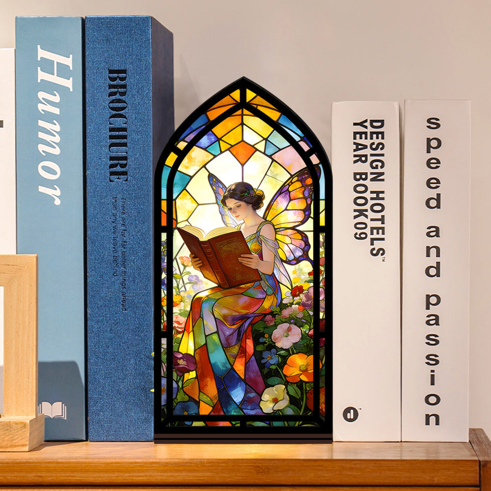 Stained glass fairy book nook with arched reading panel in black frame, books arranged around
