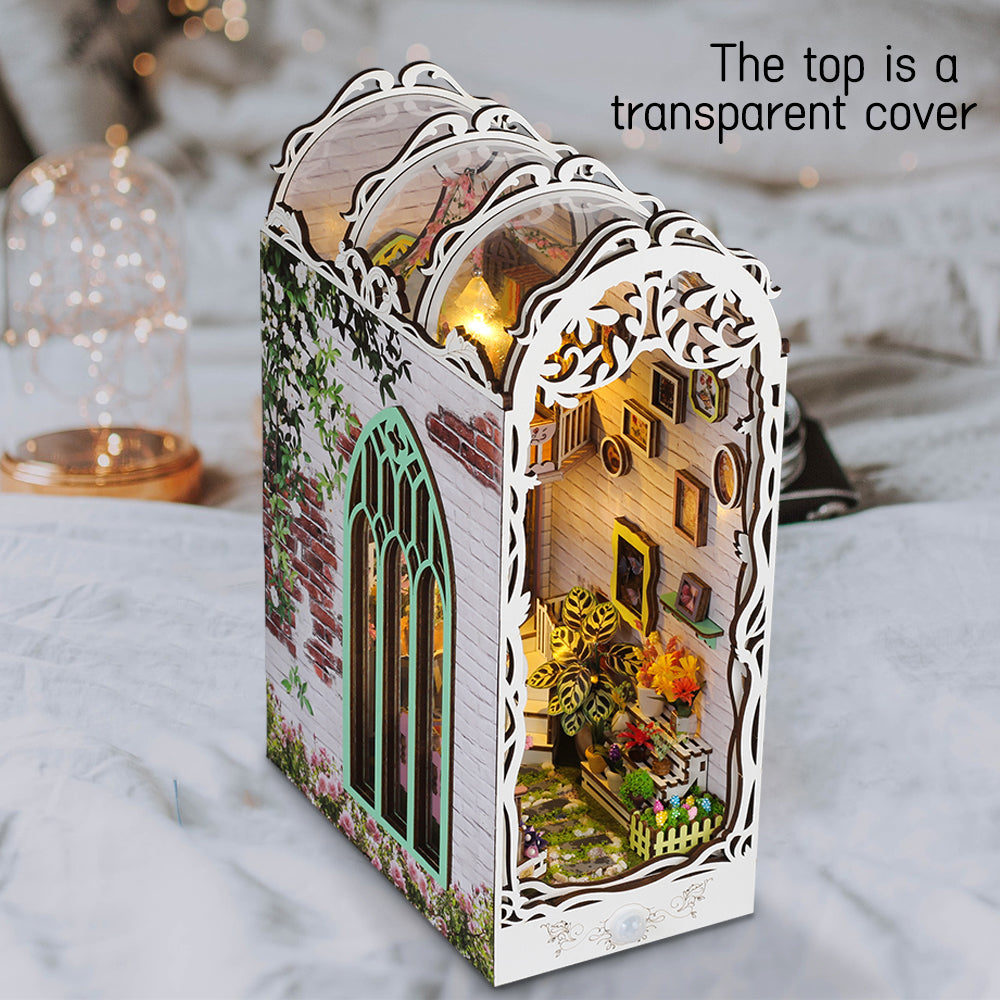 Miniature book nook kit with transparent top cover over lit garden house scene