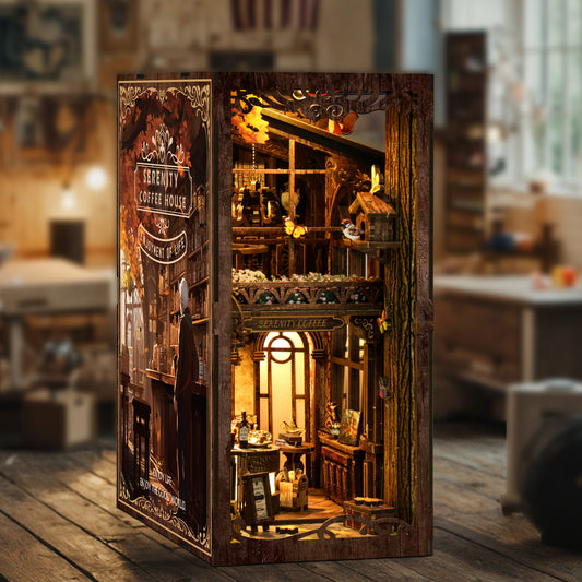 A miniature diorama of a cozy, vintage-style coffee house, complete with a small window, shelves, and various decorative elements, is displayed in a wooden frame.