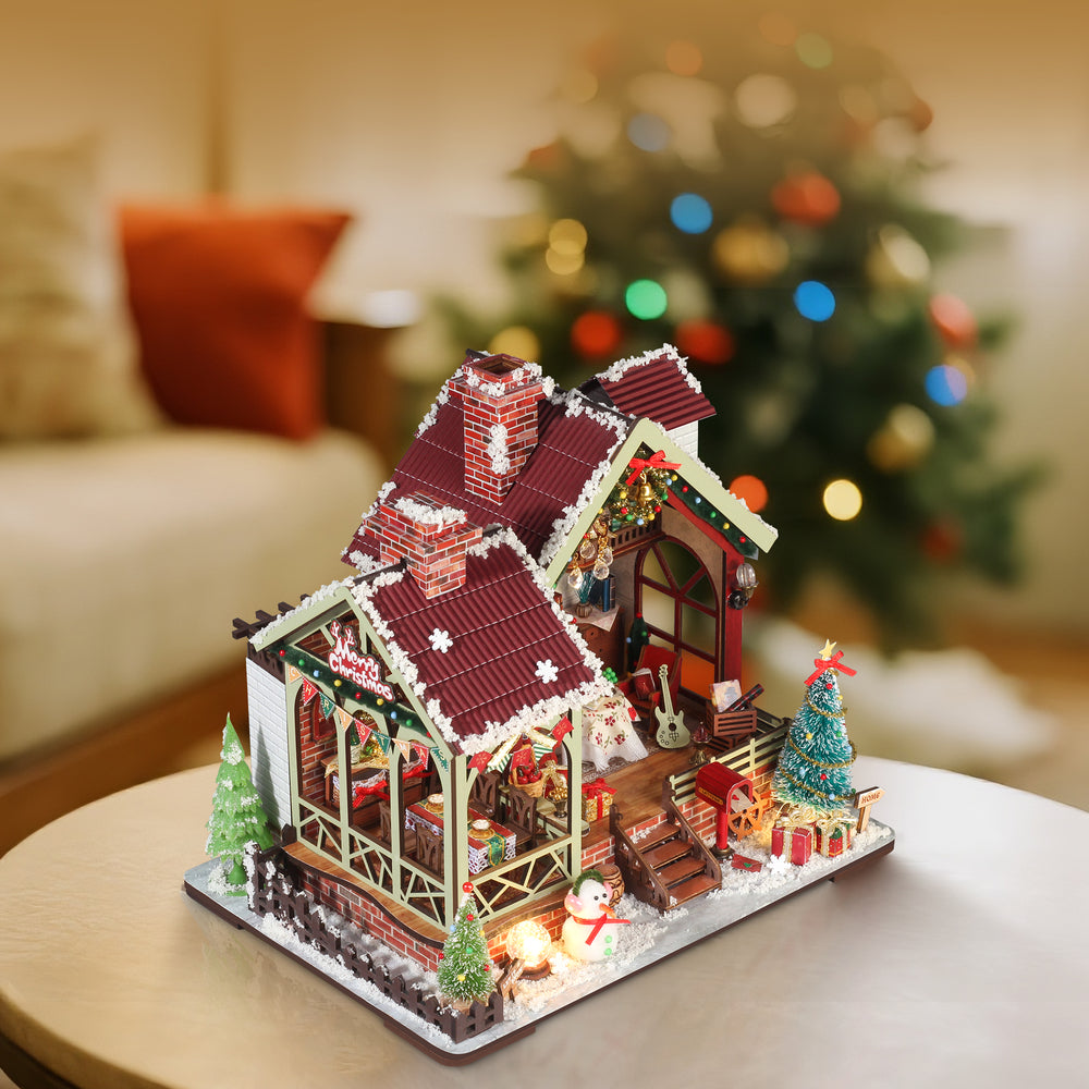 Christmas miniature dollhouse kit at angle with lit doorway, red roof, and small tree